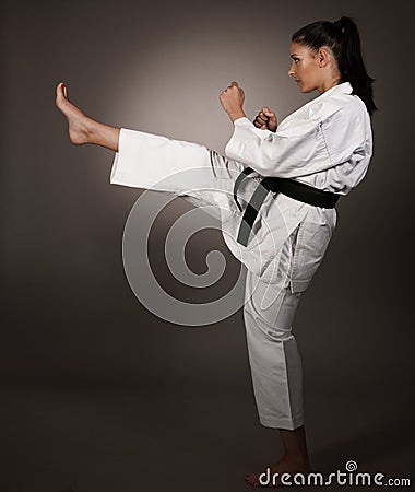 Woman in white kimono kicks high in the air - a karate martial art girl Stock Photo