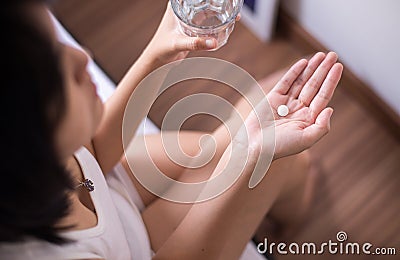 Woman with white pill painkillers on hand and a glass of water Stock Photo