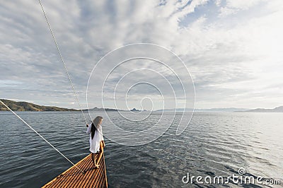 Woman in white shirt enjoying private tour on luxury wooden yacht. Ocean view Stock Photo