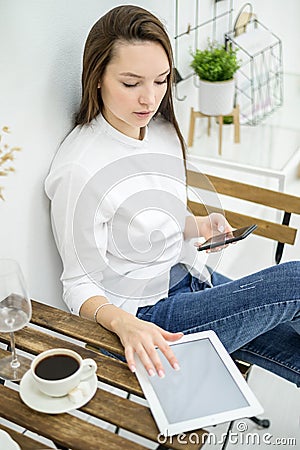 A woman in a white shirt and jeans sits in a cafe and drinks coffee. Female office worker at the lunch break talking on Stock Photo