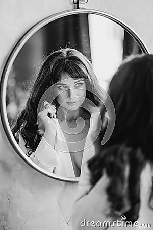 a woman in a white shirt looks at reflection in a round mirror. black and white Stock Photo