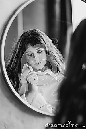 a woman in a white shirt looks at reflection in a round mirror. black and white Stock Photo