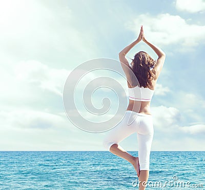 Woman in white sportswear doing yoga on a wooden pier. Sea and Stock Photo