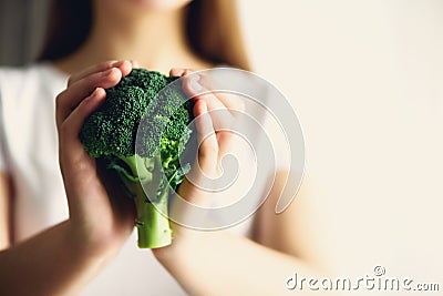 Woman in white T-shirt holding broccoli in hands. Copy space. Healthy clean detox eating concept. Vegetarian, vegan, raw Stock Photo