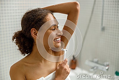 Woman in white towel shaving her armpits with razor. Depilatory procedure at bathroom Stock Photo