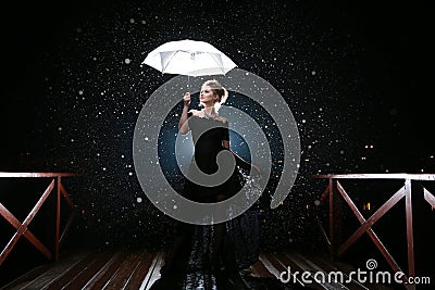 Woman with white umbrella in flash lights and rain drops Stock Photo