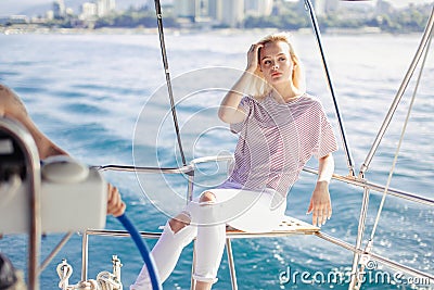 Woman on white yacht in nautical theme in open sea. Blond hair and blue clothes. Stock Photo