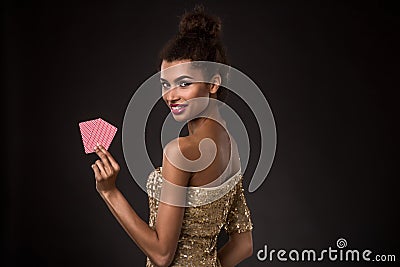 Woman winning - Young woman in a classy gold dress holding two cards, a poker of aces card combination. Stock Photo