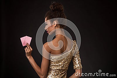 Woman winning - Young woman in a classy gold dress holding two cards, a poker of aces card combination. Stock Photo