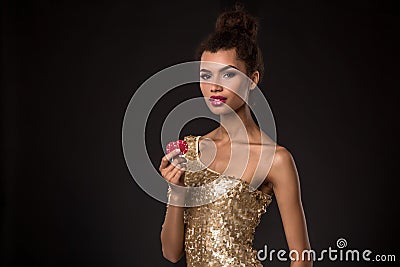 Woman winning - Young woman in a classy gold dress holding two red chips, a poker of aces card combination. Stock Photo