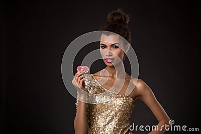 Woman winning - Young woman in a classy gold dress holding two red chips, a poker of aces card combination. Stock Photo