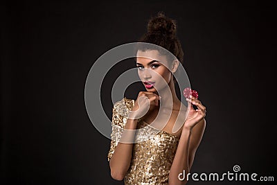 Woman winning - Young woman in a classy gold dress holding two red chips, a poker of aces card combination. Stock Photo