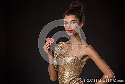 Woman winning - Young woman in a classy gold dress holding two red chips, a poker of aces card combination. Stock Photo