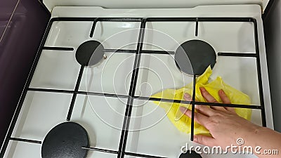 Woman cleaning a gas stove with yellow cloth Stock Photo