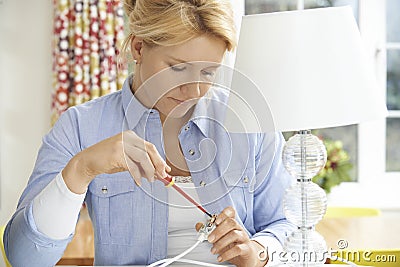 Woman Wiring Electrical Plug On Lamp At Home Stock Photo
