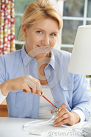 Woman Wiring Electrical Plug On Lamp At Home Stock Photo