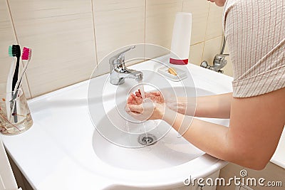 A woman wishing hands with water in bathroom sink. Desease prevention and hygiene concept. Useful, good habit Stock Photo