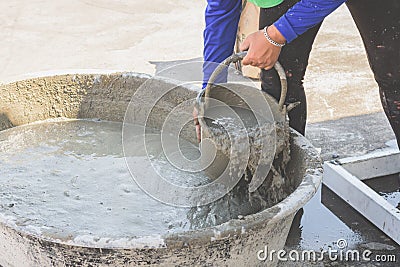 Woman woker scoop mixed cement into a bucket. Stock Photo