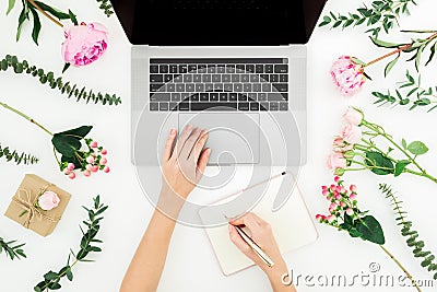 Woman work with laptop. Workspace with female hands, laptop, notebook and pink flowers on white background. Top view. Flat lay Stock Photo