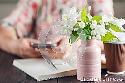 Woman work at table with flowers bouquet ana take away coffee Stock Photo