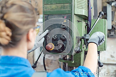 Woman worker in metal workshop operating power drill Stock Photo