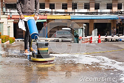 Woman worker using scrubber machine for cleaning polishing concrete floor. Stock Photo