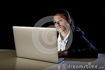 Woman working in darkness on laptop computer late at night looking stressed bored and tired Stock Photo