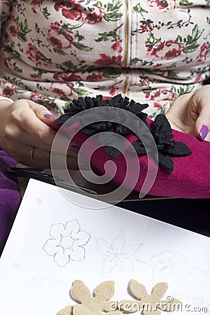 Woman working on a headdress. Sewing flower of cloth. Stock Photo
