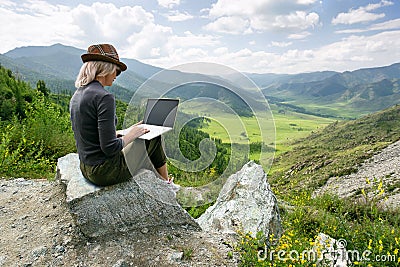 Woman working on her computer on the top of the mountain. Remote work Stock Photo