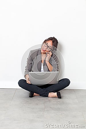 Woman working on her laptop, talking on phone sitting on floor Stock Photo