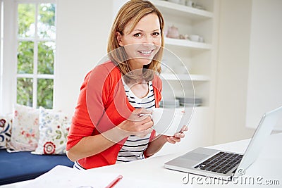 Woman Working From Home Using Laptop In Kitchen Stock Photo