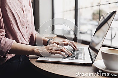 Woman working on laptop computer, female hands typing keyboard closeup, businesswoman or student girl using laptop at cafe Stock Photo