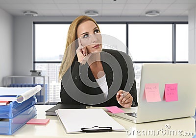 Woman working at laptop computer sitting on the desk absent minded and thoughtful sitting at business district office Stock Photo