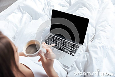 Woman working on laptop and having morning coffee in bed Stock Photo