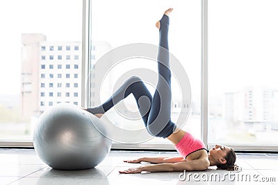 Woman working out with exercise ball in gym. Pilates woman doing exercises in the gym workout room with fitness ball. Fitness woma Stock Photo