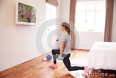 Woman Working Out To Fitness DVD On TV In Bedroom Stock Photo