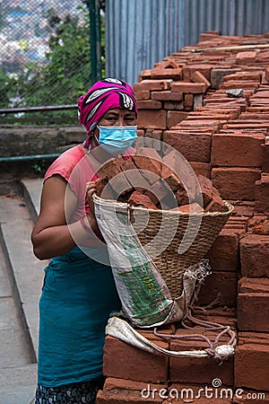 Woman working to stack bricks into a basket Editorial Stock Photo