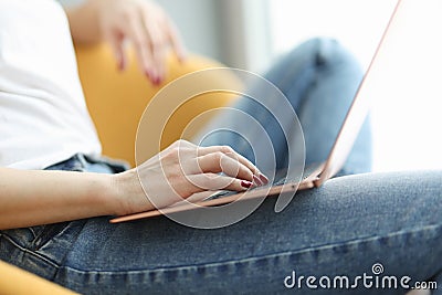 Woman works on laptop while sitting in yellow chair Stock Photo