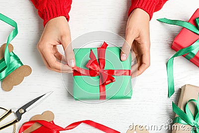 Woman wrapping Christmas gift at white wooden table Stock Photo