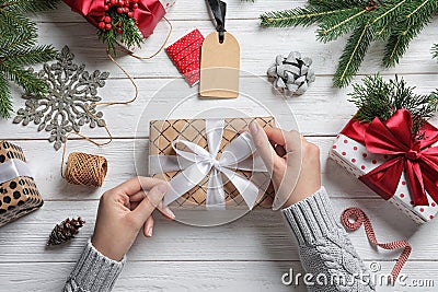 Woman wrapping Christmas gift at wooden table Stock Photo