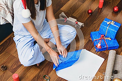 Woman wraps Christmas gifts sitting at home on floor Stock Photo