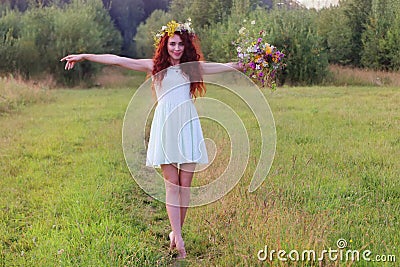 Woman in wreath with bunch of flowers on meadow at summ Stock Photo