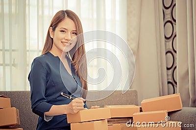 Woman writing address and sending package for online business Stock Photo