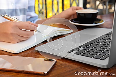 Woman writing blog content in notebook at table Stock Photo