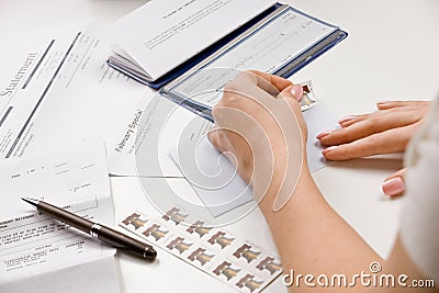 Woman writing checks from checkbook Stock Photo