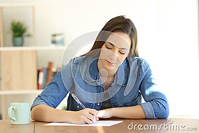 Woman writing a letter on a table at home Stock Photo