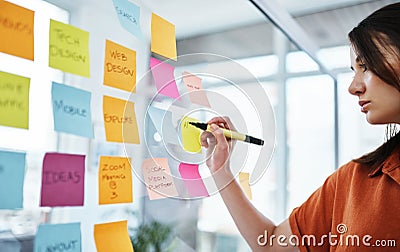 Woman writing notes, brainstorming with ideas on glass board and sticky note, planning in office with focus. Creative Stock Photo