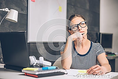 Woman writing notes and contemplating at the office Stock Photo