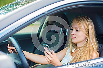 Woman writing sms while driving car. Stock Photo