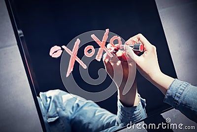 Woman writing xoxo on a mirror with red lipstick. Stock Photo
